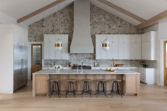 Modern kitchen with island, white cabinets, and stone accent wall
