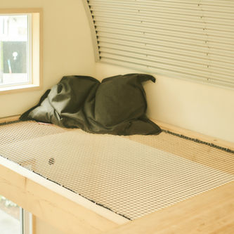 Lit en filet, oreiller vert, petite fenêtre