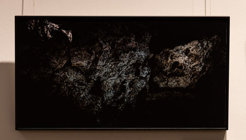 Scared Baby by Roee Baldinger (Cerno Argus). High-contrast dark fine art photography of a jagged, granular rock texture with sharp shadows carving out an infant facial profile with wide, fearful eyes. Part of the Psychosis of a Matter sub-series.