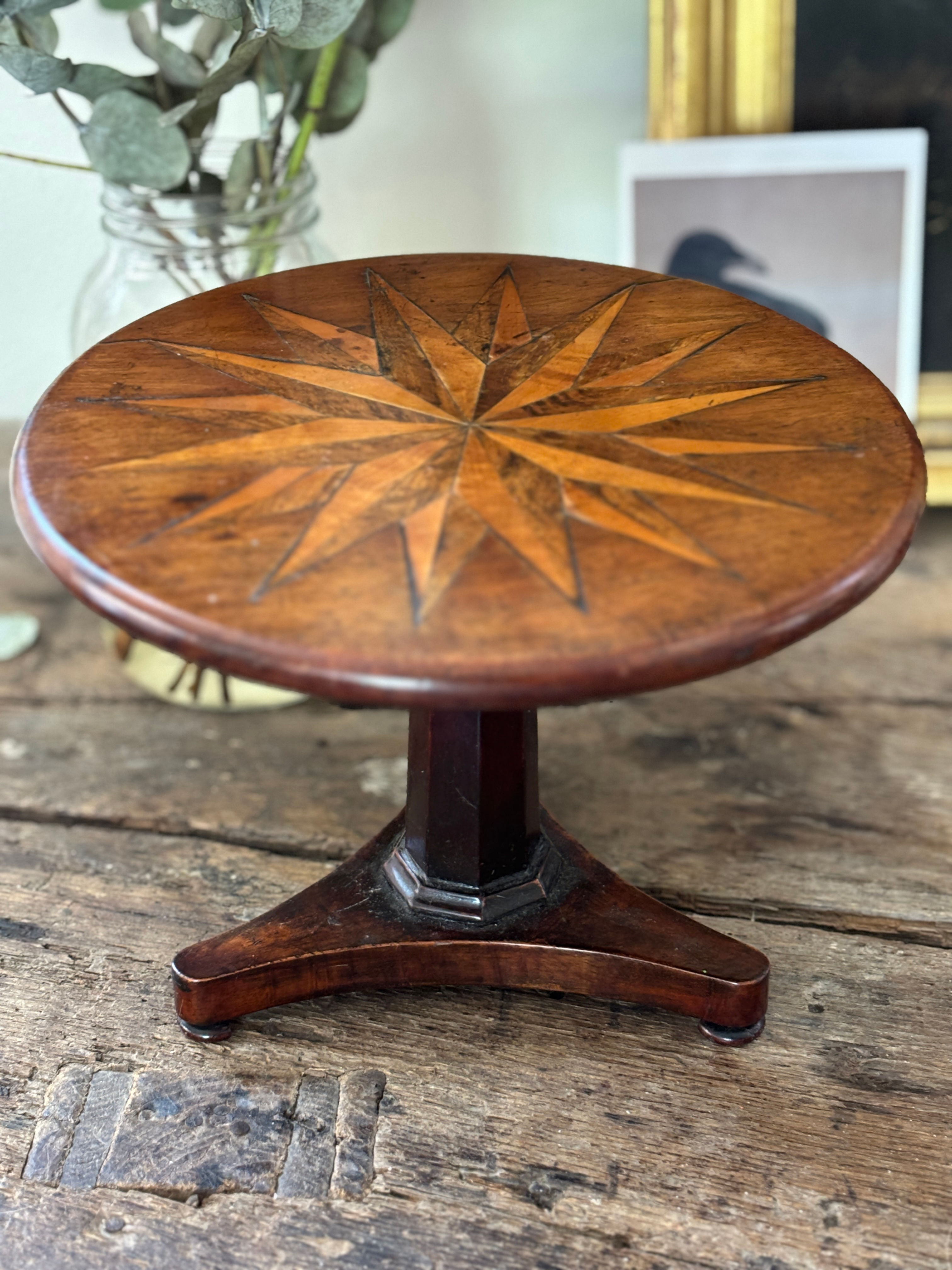 Miniature mahogany pedestal table with compass star inlay.