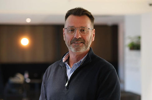 “Professional portrait of a mature man with short dark hair and a neatly trimmed beard, we