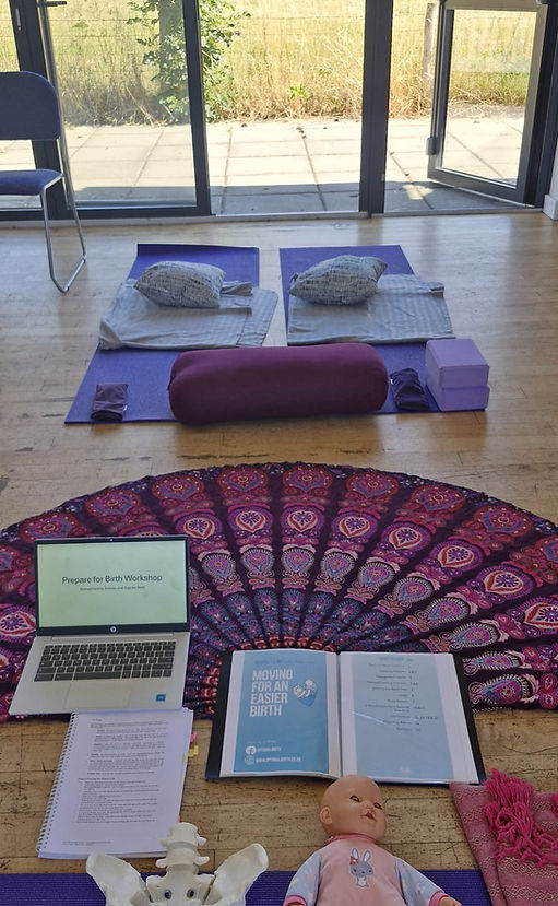 Workshop setup for a ‘Prepare for Birth’ class. Two yoga mats with cushions and bolsters are arranged in front of large windo