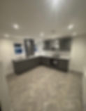 Modern grey fitted kitchen renovation with herringbone flooring, white subway tiles, integ