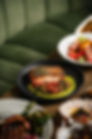 a professionally designed meal of salmon and lobster dishes on a table with a green velvet banquette