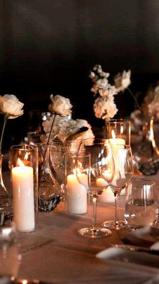 A cande-lit dinner table with glasses and roses.