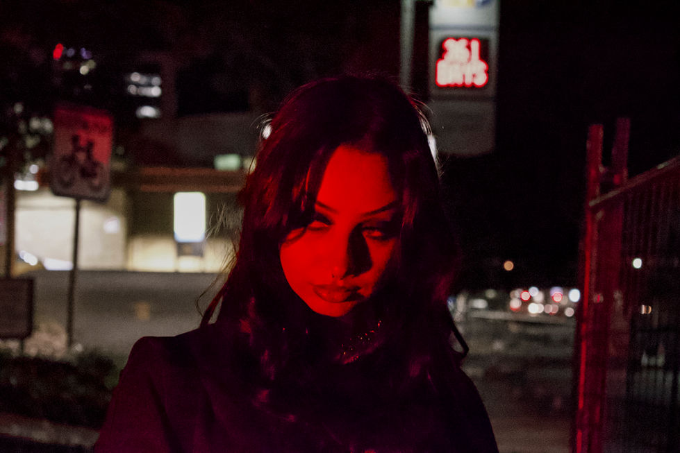 Neon lights at night shining on model close up staring down lens