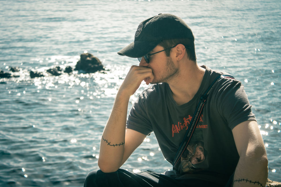 Man staring out to glimering ocean with rocky background