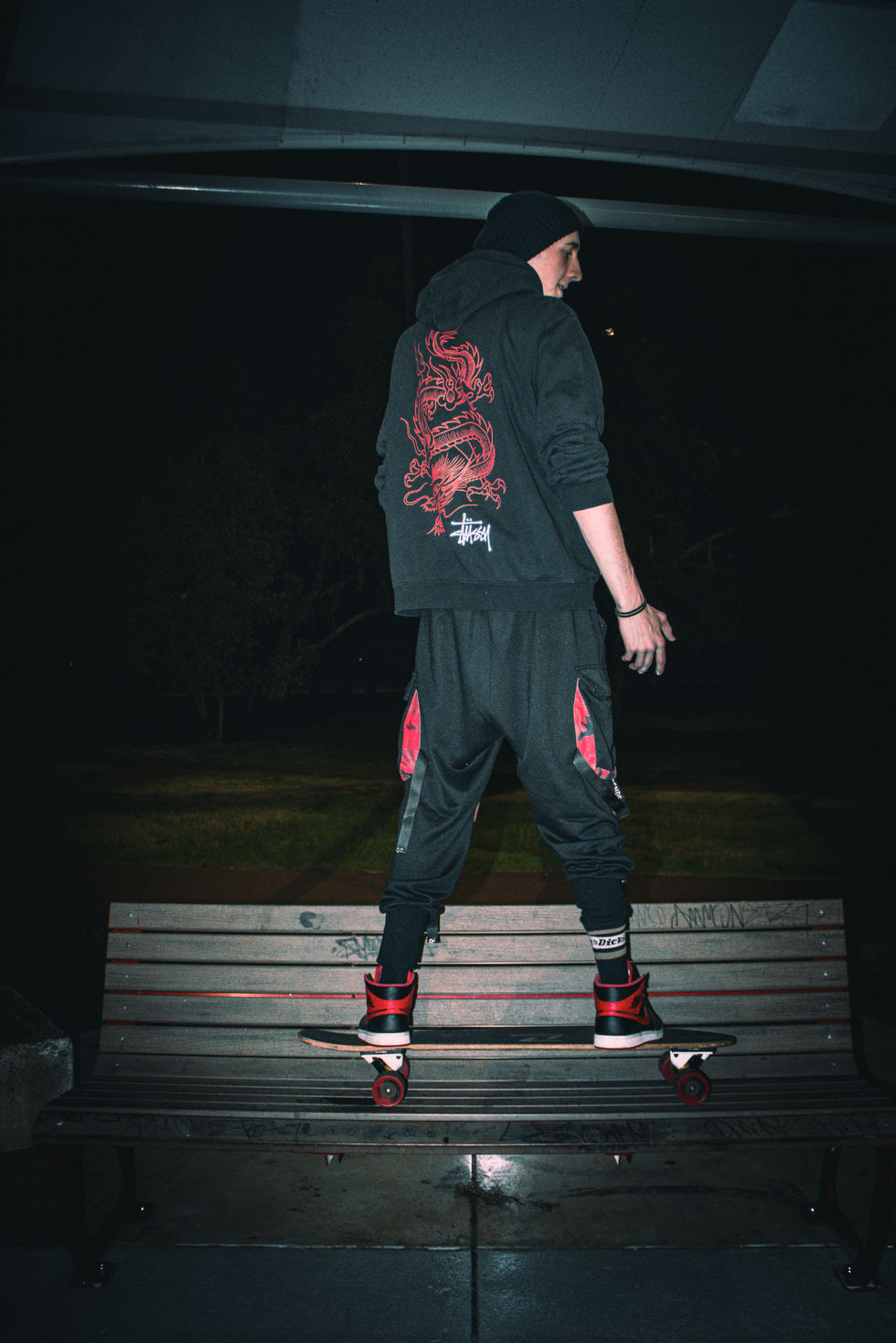 Close up of man on skateboard staring out in skatepark at night