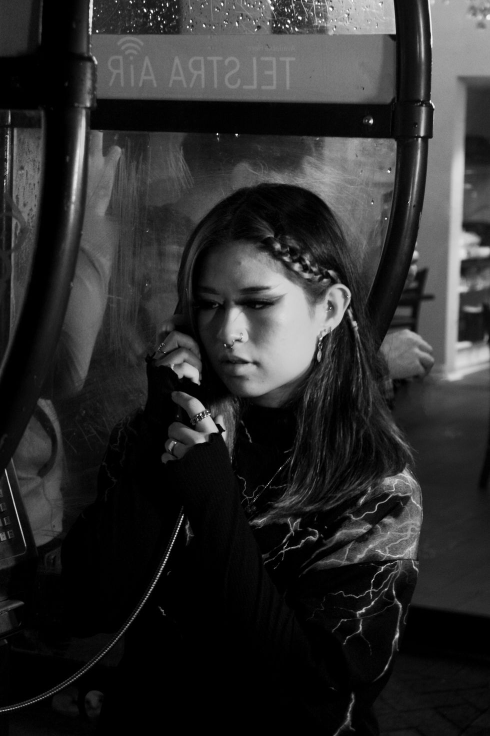 Late night photo in Perth city of woman taking phone call from phone booth