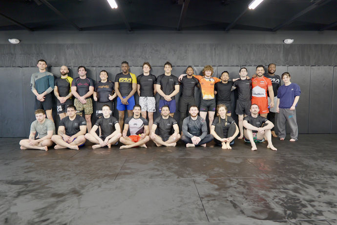 Students lined up along the wall after a seminar with Noah Shaffner at Connecticut Submission Grappling, with sweat on the mats from intense training