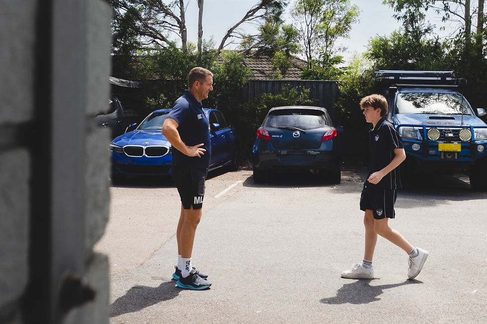 Man and boy in sports attire converse in parking lot