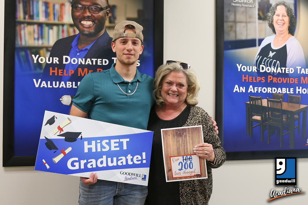 Tyce holding the Goodwill Acadiana HiSET Graduate sign alongside Janet, our Adult Education Instructor, who's celebrating her 200th graduate!