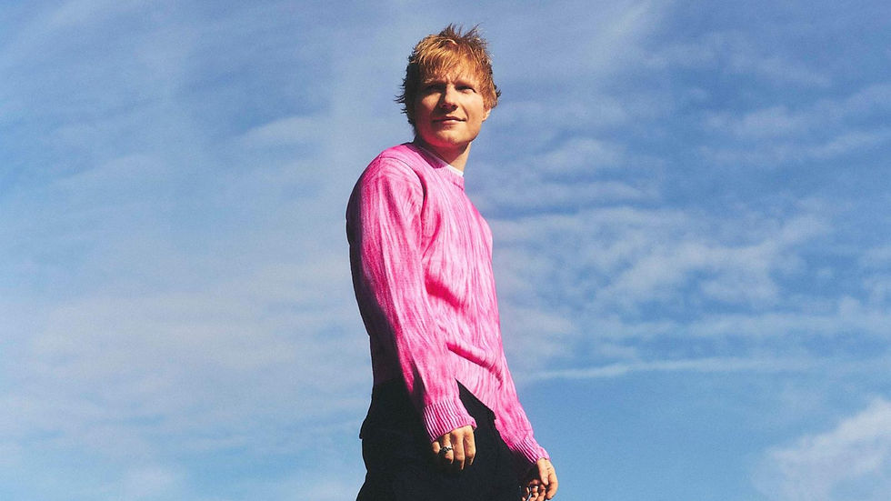 Ed sheeran in the center of the photo with clouds in the background.