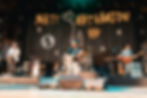 Live band on stage performing under a Matt Nathanson backdrop, with guitars, drums, and warm orange lighting.