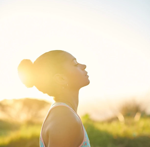 Empowered woman looking up to the sky with sunset