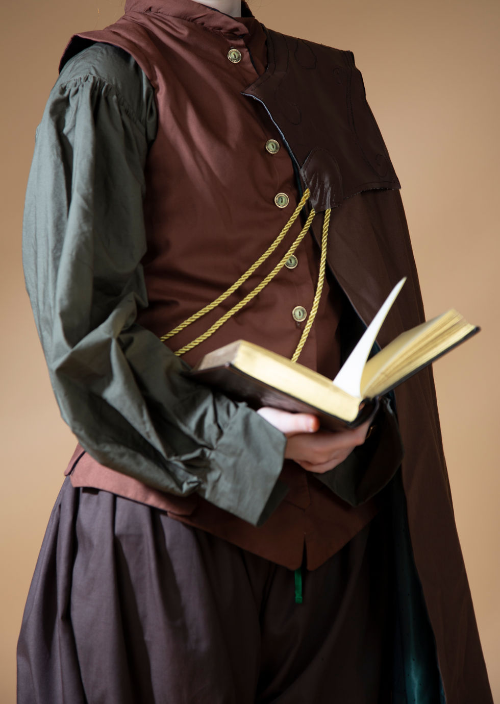 a person wearing a brown vest and a green shirt is holding a book
