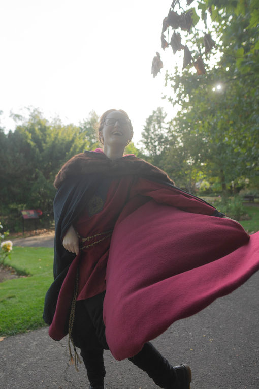 a woman wearing a red shirt and a black cloak.