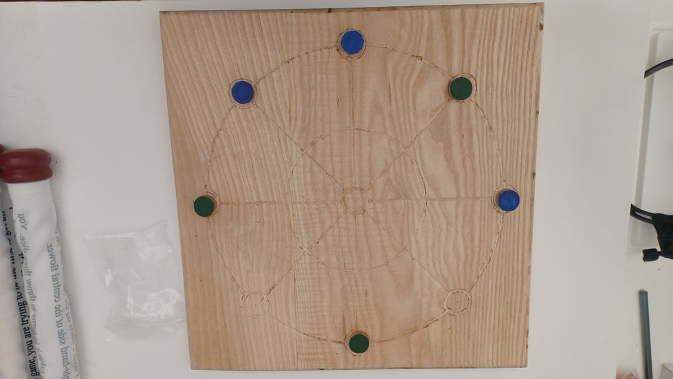 a wooden board with blue and green circles on it for playing Terni Lapilli