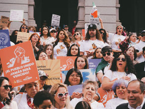 A crowd of Latinos holding signs