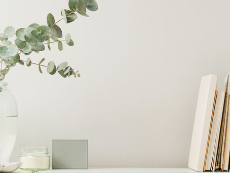 A vase with some greenery and a stack of books against a white background.