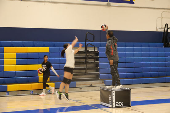 Coach holding volleyball for player during training session