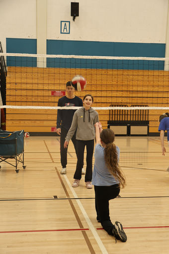 Young players practicing volleyball in a gymnasium.
