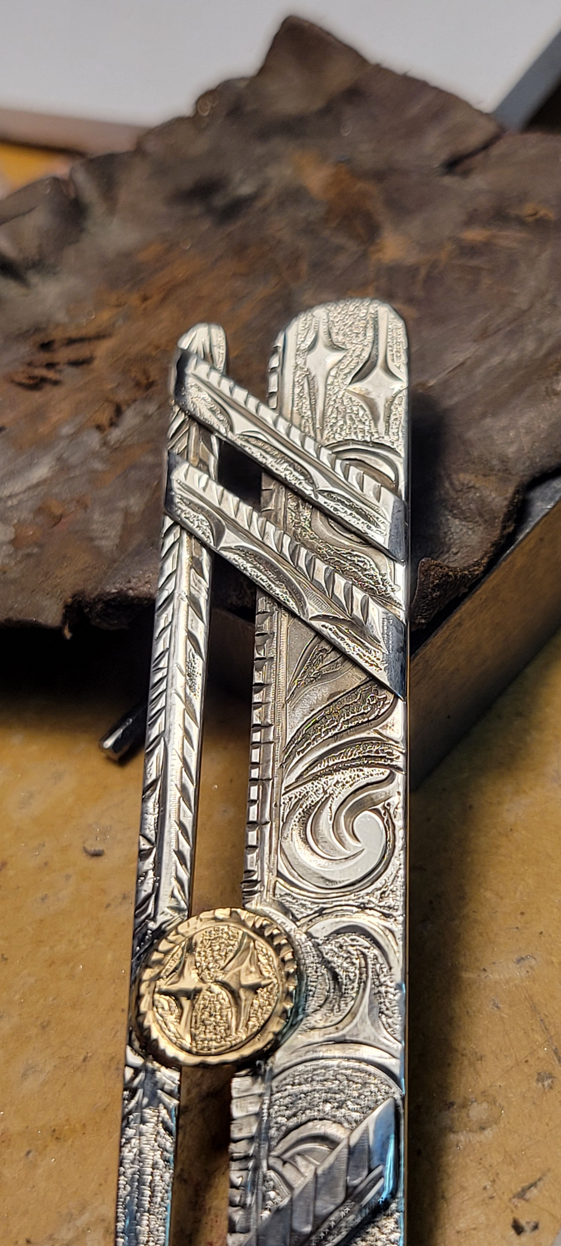 Intricately detailed silver money clip with engraved floral designs on it.