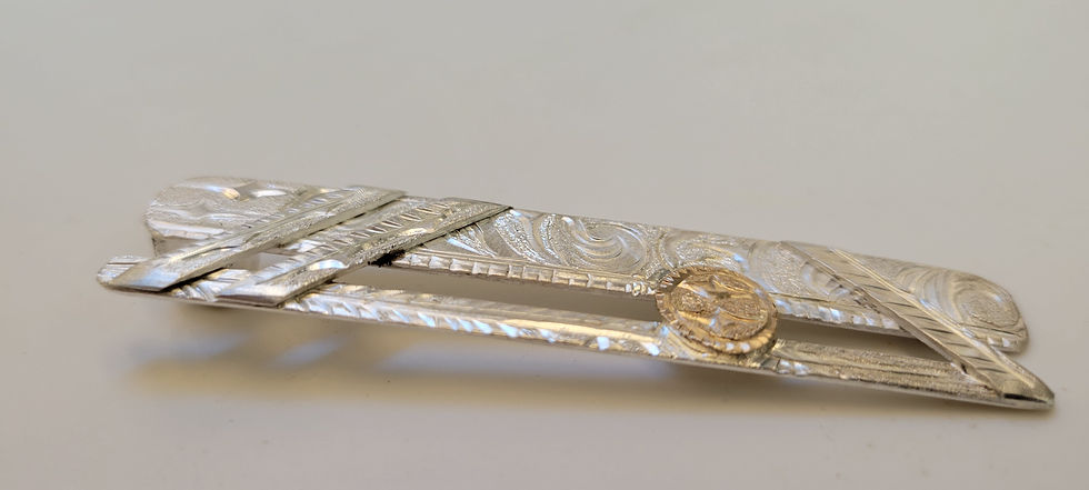 Thumbnail: Close-up of a silver tie clip with engraved details and a gold accent.