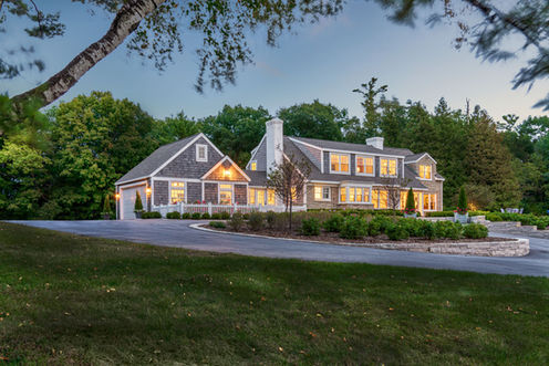 Traditional luxury home exterior at dusk with landscaped lawn and driveway