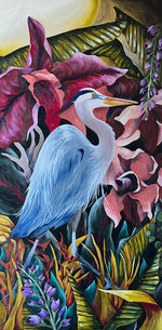 Blue heron standing in a colorful jungle with a large moon and large bright pink flowers in the background.