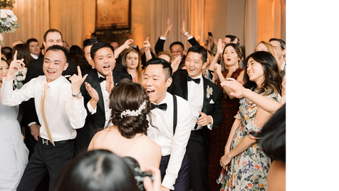 Group of wedding guests dressed in formal attire smiling and cheering together.