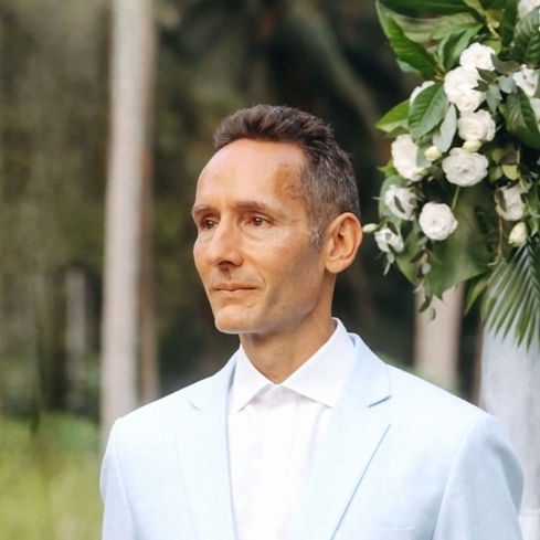 Man in light blue suit at a wedding, looking off camera.