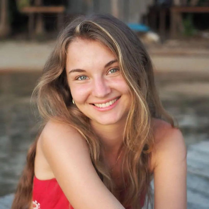 Smiling woman with long hair, wearing a red top, smiling at the camera.