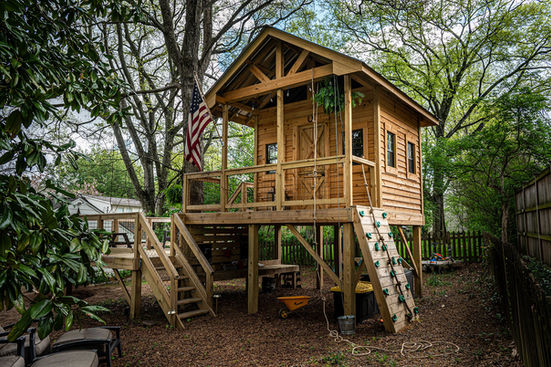 Elevated custom wooden fort with American flag and front balcony, designed by Firefly Forts Atlanta for backyard family play.