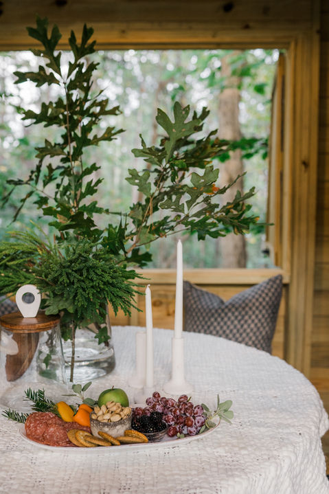 Table setting with candles, greenery, grapes, and citrus fruits on display.