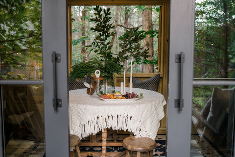 Table set with food and candles, against the forest view background.