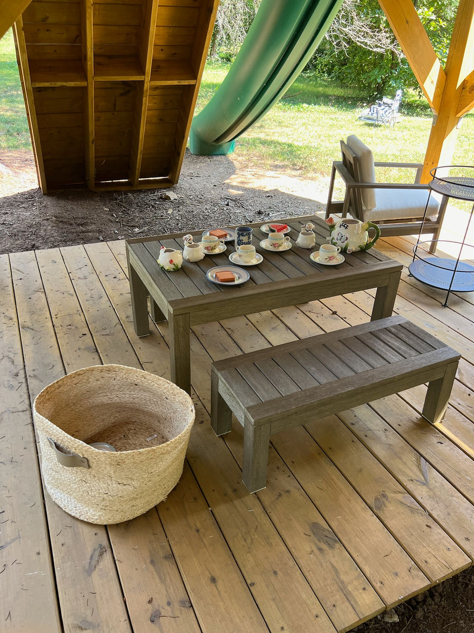 Outdoor wooden table set with food and drinks for a gathering.