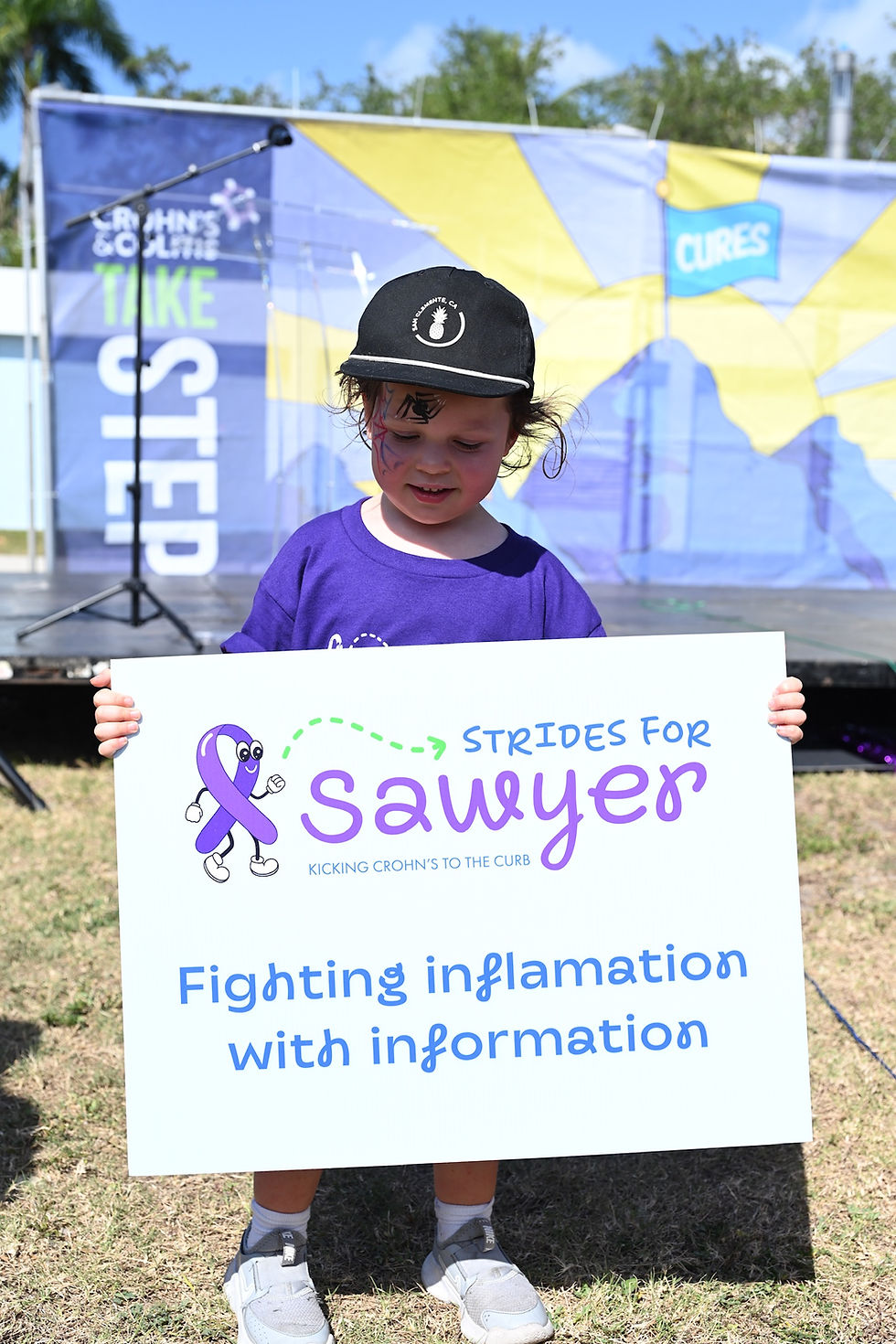 Child holding Strides for Sawyer sign at Take Steps Walk supporting Crohn’s disease and IBD awareness