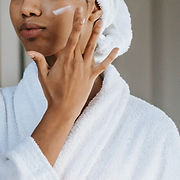Woman applying skin cream to her face.