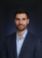 Professional young woman in a mustard blazer holding a coffee cup, smiling in a modern office environment