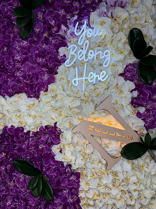 Floral wall with "You Belong Here" and "Nelly's" signage, decorative background.