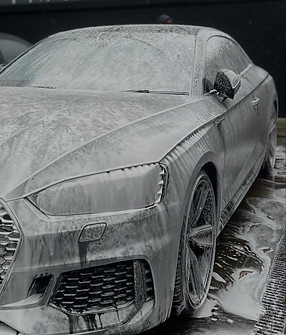 Car covered in foam being washed by Visuals car detailing, Audi model, side view, detailing process.