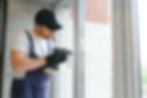 Workman in overalls installing or adjusting plastic windows in the living room at home..jp