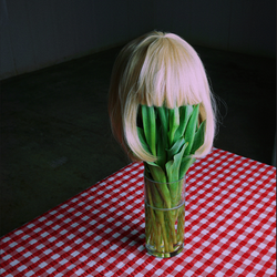 Wig Out by Mishele — a pale synthetic wig over a vase of tulips on red gingham.