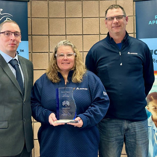 Jeremiah Johnston, Michigan Works! Apprenticeship Specialist, stands in front of Race to Talent banners with Amrize’s Michele Martel (HR Manager) holding their award and Jeff Purol (Powerhouse & Electrical Manager) (recognized for their Electrical Maintenance Registered Apprenticeship Program)