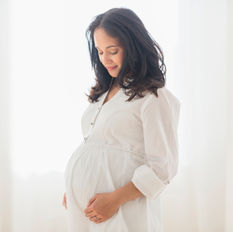 a pregnant woman holding her baby bump and smiling down at it
