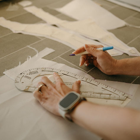 Designer Barbara Kavchok measuring and cutting fabric by hand for a custom wedding dress in her Bethlehem, PA bridal atelier.
