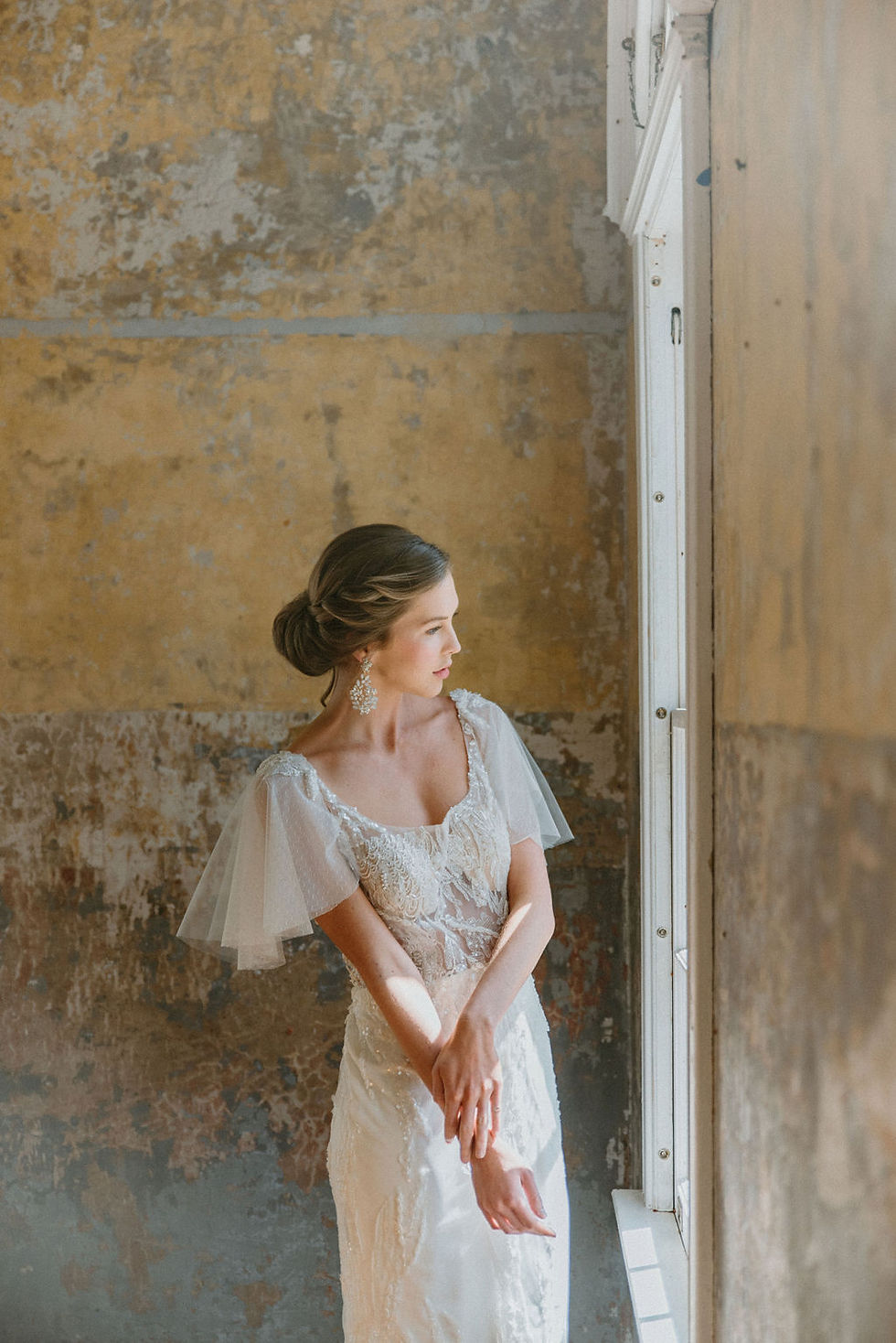 Thumbnail: Close up of the bodice of a heavy beaded and embroidered wedding dress with detachable flutter sleeves and a soft square neck