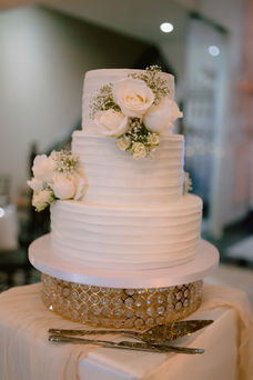 Three-tier white wedding cake with floral details at Hotel El Convento reception