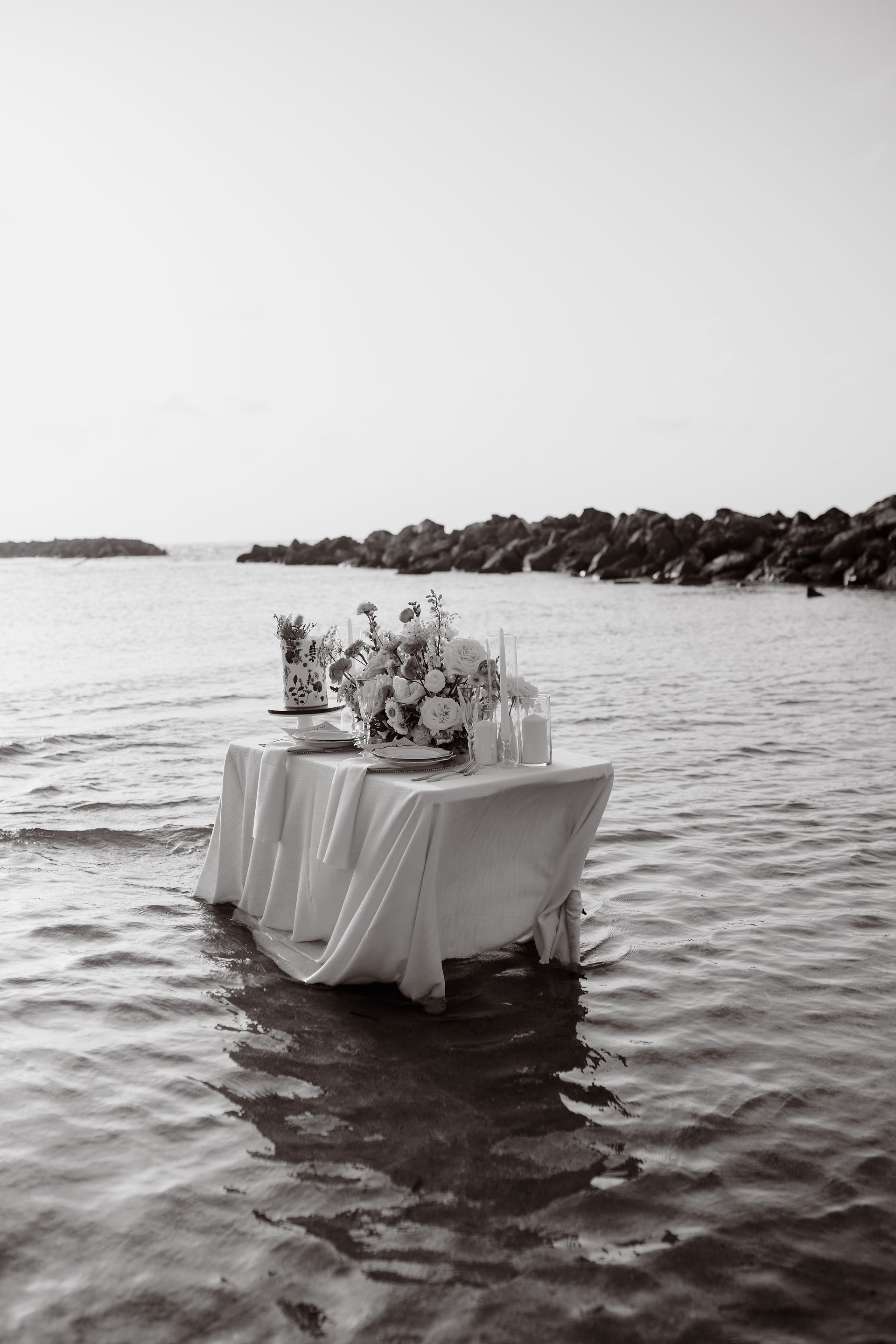 Romantic table surrounded by water with flowers and cake